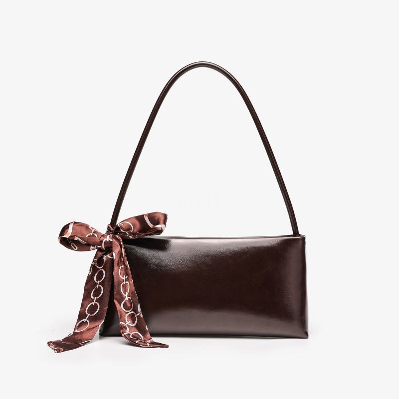 A professional product shot of a glossy, dark chocolate brown rectangular handbag featuring a thin top handle and a decorative patterned satin scarf tied to the side